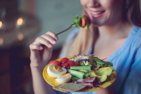 A woman eating a plate of nutrient-rich foods that promote dental and gum health in Columbus, OH