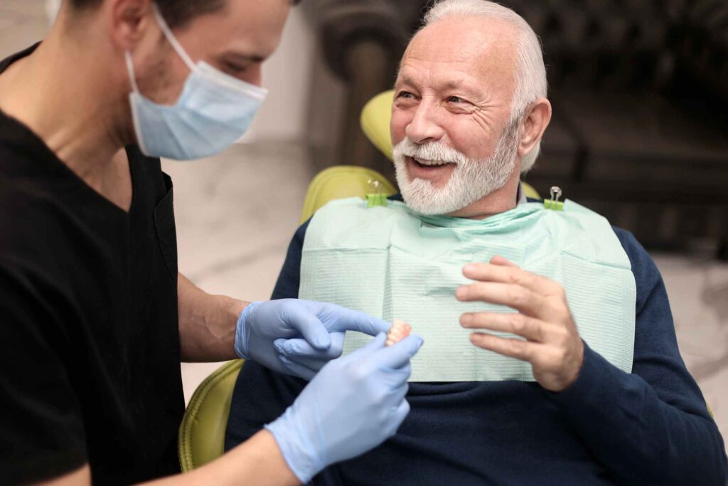 A senior patient reviewing tooth replacement solutions with a dentist in Columbus, OH